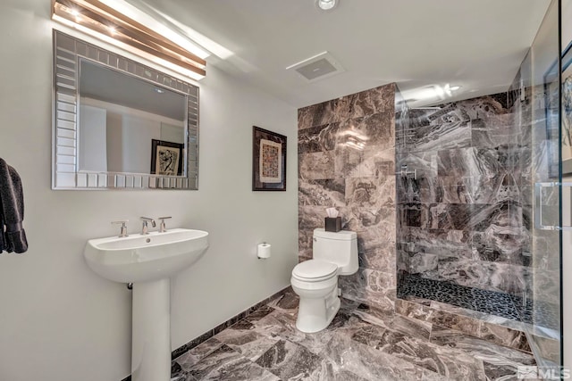 bathroom featuring toilet, a sink, baseboards, marble finish floor, and a stall shower