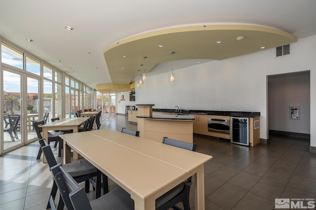 dining area with recessed lighting, beverage cooler, dark tile patterned flooring, and expansive windows
