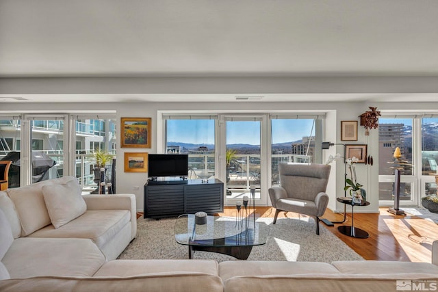 living area with a healthy amount of sunlight, visible vents, baseboards, and wood finished floors