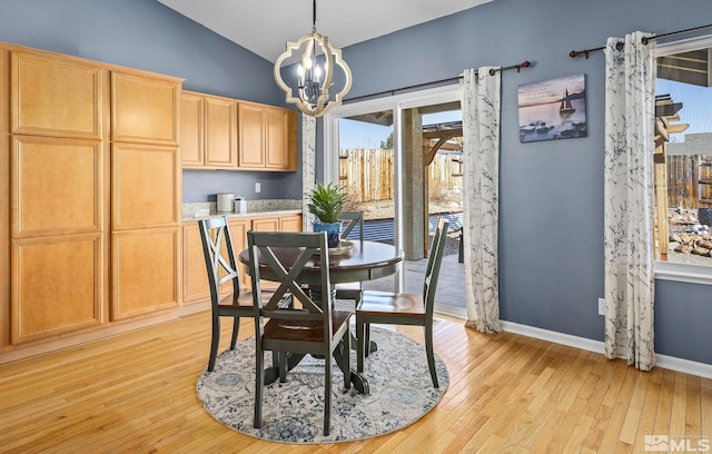 dining area featuring lofted ceiling, light wood-style flooring, baseboards, and an inviting chandelier