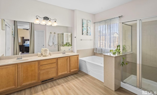 ensuite bathroom featuring connected bathroom, a garden tub, a sink, and a shower stall