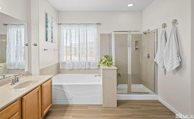 bathroom with a bath, a shower stall, wood finished floors, and vanity