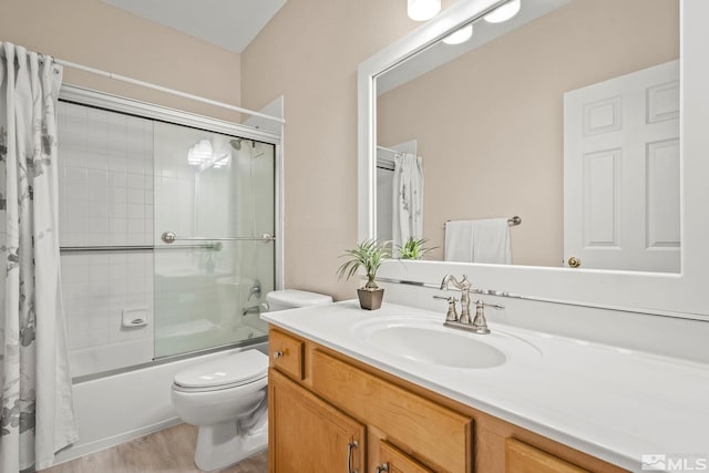 full bath with enclosed tub / shower combo, wood finished floors, vanity, and toilet