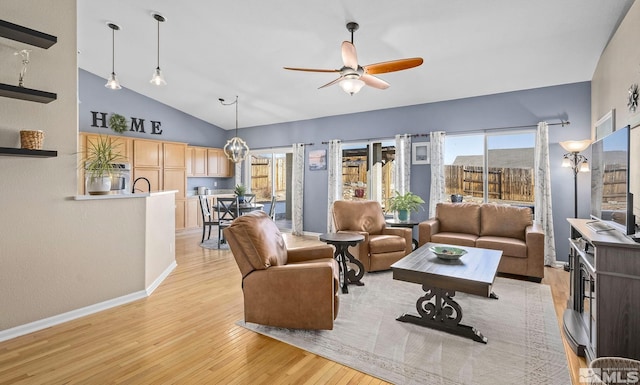 living room featuring light wood-style flooring, high vaulted ceiling, ceiling fan, and baseboards