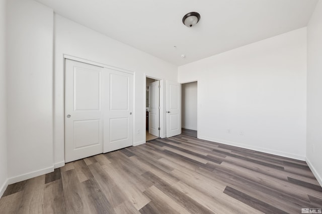 unfurnished bedroom featuring a closet, wood finished floors, and baseboards