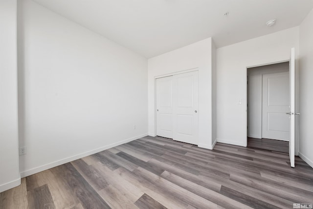 unfurnished bedroom featuring a closet, baseboards, and wood finished floors