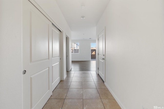 hallway with light tile patterned flooring and baseboards