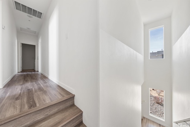 hall with wood finished floors, visible vents, and baseboards