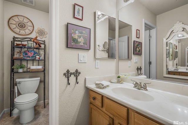 bathroom with toilet, baseboards, visible vents, and vanity