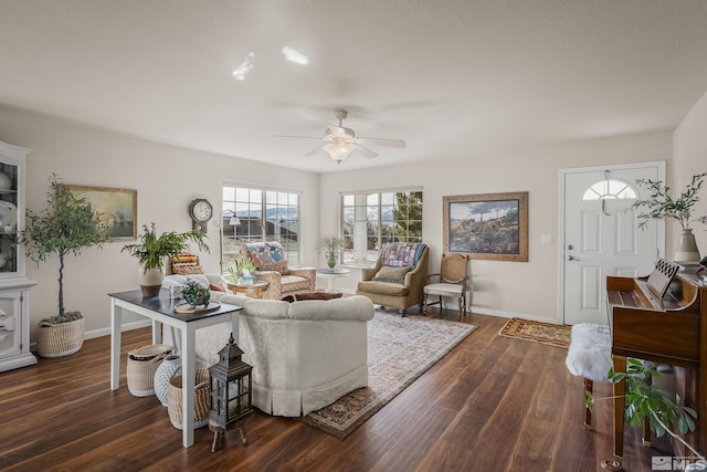 living area featuring dark wood-style flooring, a ceiling fan, and baseboards