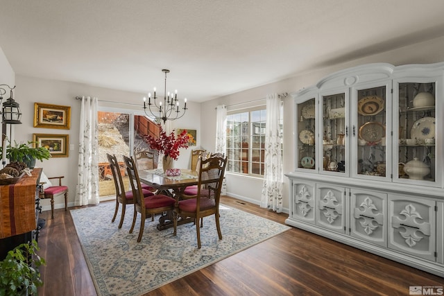 dining area featuring baseboards, dark wood finished floors, and a notable chandelier