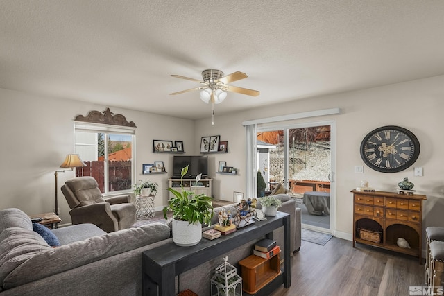 living area featuring dark wood-style floors, ceiling fan, a textured ceiling, and baseboards