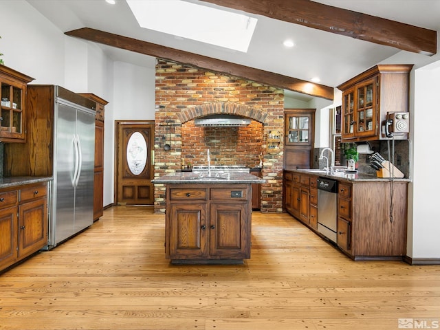 kitchen with vaulted ceiling with beams, appliances with stainless steel finishes, light wood finished floors, and glass insert cabinets