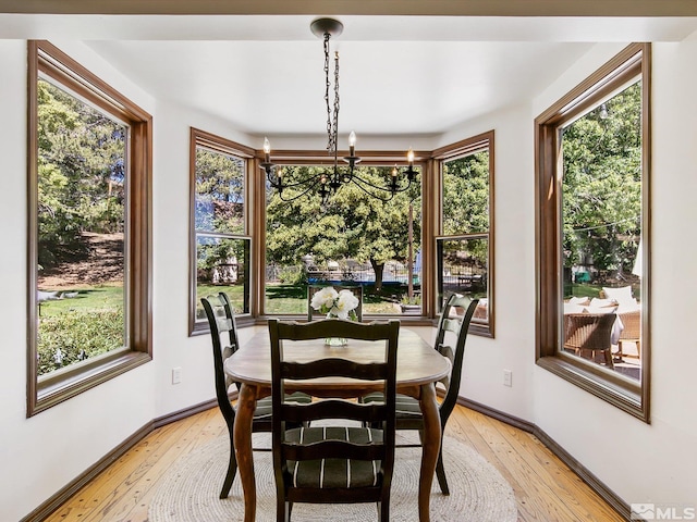 dining area featuring baseboards, an inviting chandelier, and light wood-style floors