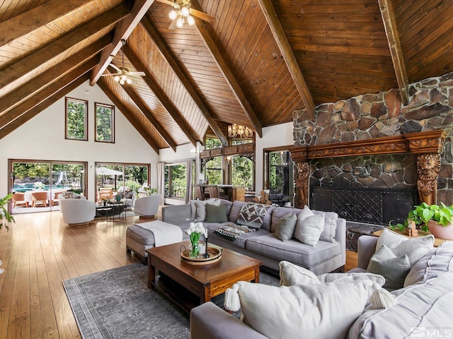 living area with wood-type flooring, a stone fireplace, high vaulted ceiling, wooden ceiling, and beamed ceiling