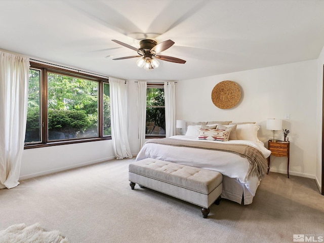 carpeted bedroom with ceiling fan and baseboards