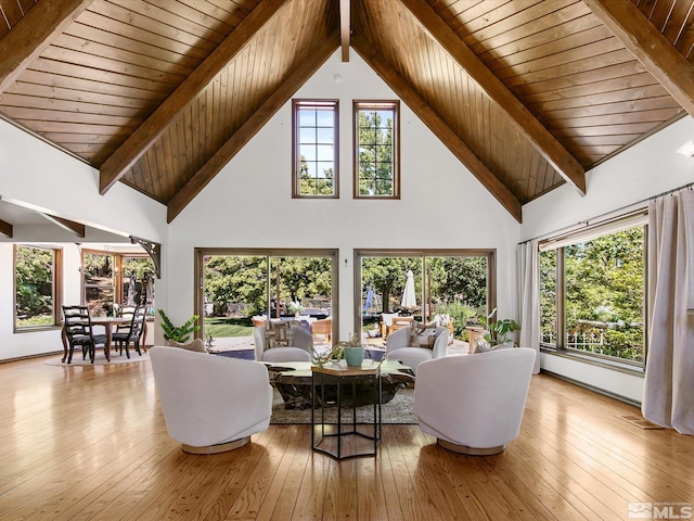 living room with high vaulted ceiling, plenty of natural light, beamed ceiling, and hardwood / wood-style flooring