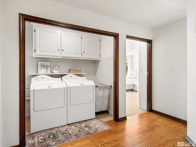 washroom featuring cabinet space, light wood-style flooring, baseboards, and independent washer and dryer