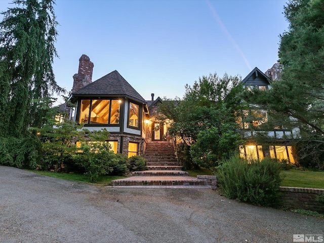 exterior space with stone siding, a chimney, and stairway