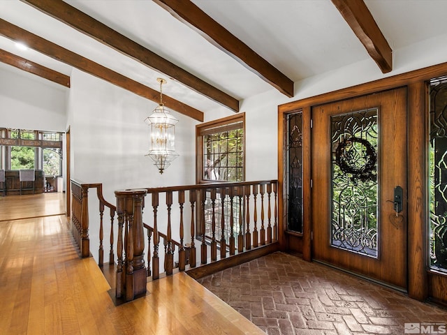 interior space with vaulted ceiling with beams, brick floor, plenty of natural light, and a chandelier