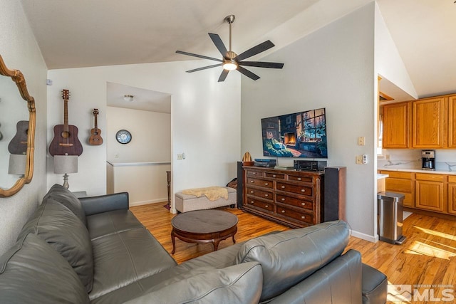 living area featuring lofted ceiling, baseboards, ceiling fan, and light wood finished floors