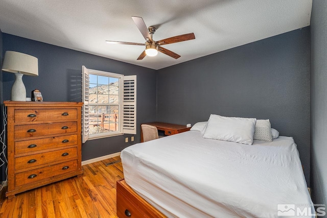 bedroom with wood finished floors, a ceiling fan, and baseboards