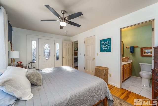 bedroom with light wood-style flooring, ceiling fan, ensuite bath, washer / dryer, and baseboards