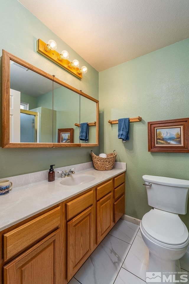 bathroom with toilet, marble finish floor, a textured ceiling, and vanity