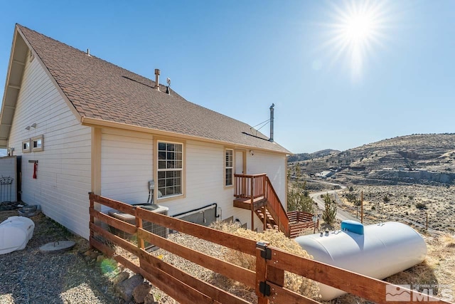 back of property with roof with shingles, fence, and a mountain view