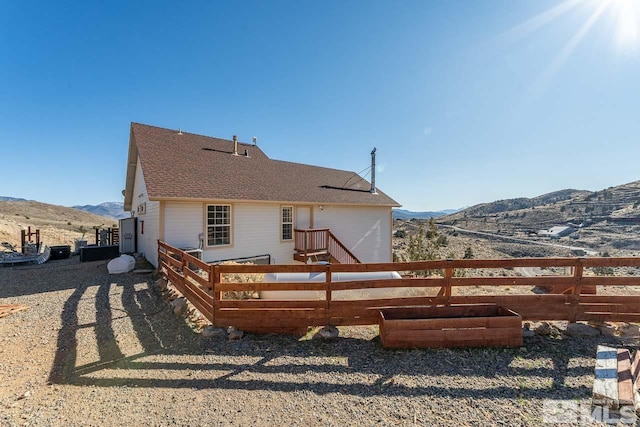 back of house featuring a shingled roof, fence, and a mountain view