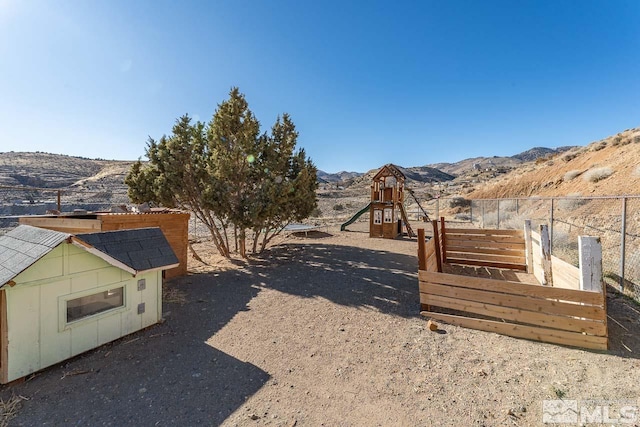 view of yard with a playground, a mountain view, and fence