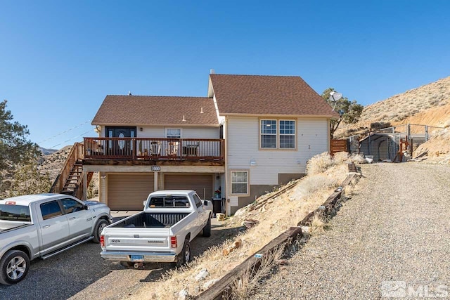 view of front of property with a garage, roof with shingles, fence, and stairway