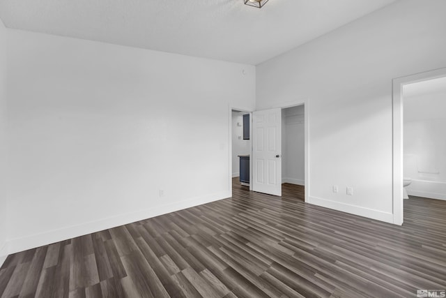 unfurnished bedroom with dark wood-type flooring, a closet, and baseboards