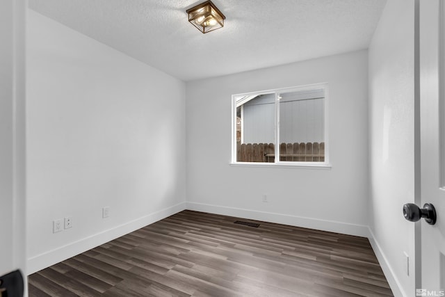 empty room with visible vents, a textured ceiling, baseboards, and wood finished floors