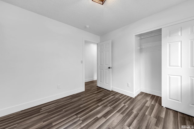 unfurnished bedroom featuring a closet, baseboards, dark wood finished floors, and a textured ceiling