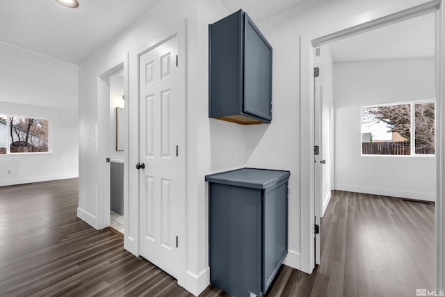 hallway featuring dark wood-style flooring and baseboards