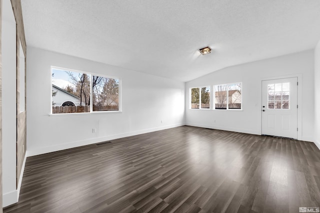 unfurnished living room with a textured ceiling, vaulted ceiling, dark wood finished floors, and visible vents