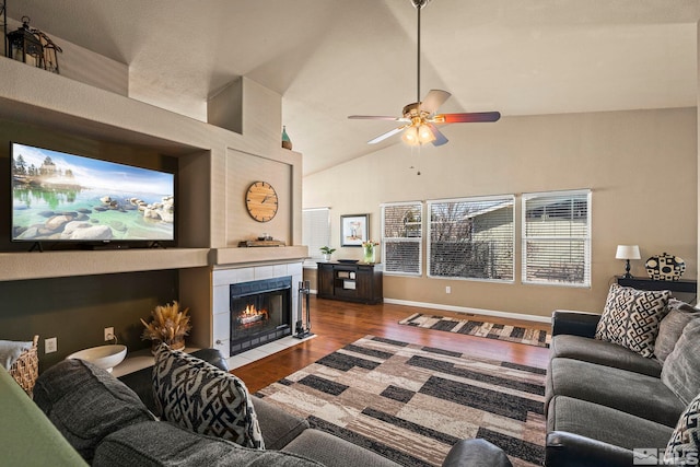 living area with high vaulted ceiling, a fireplace, wood finished floors, and a ceiling fan