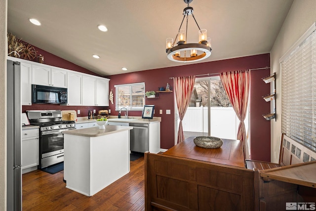 kitchen with white cabinets, lofted ceiling, dark wood-type flooring, stainless steel appliances, and a sink