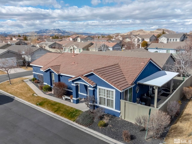 view of front of house featuring a mountain view, a tile roof, a residential view, and stucco siding