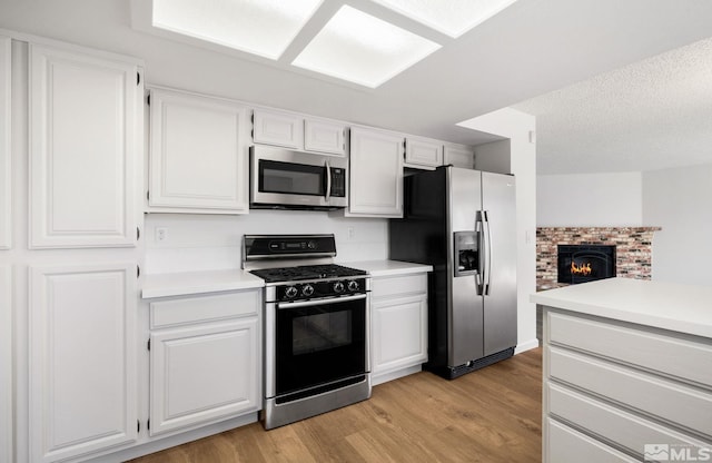 kitchen featuring stainless steel appliances, light countertops, light wood-style flooring, and white cabinets