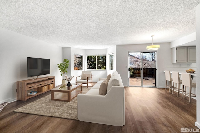 living area featuring a textured ceiling, baseboards, and wood finished floors