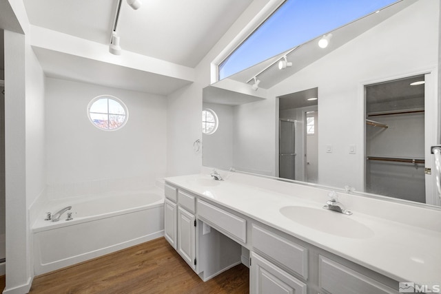 bathroom with lofted ceiling, double vanity, a sink, and wood finished floors