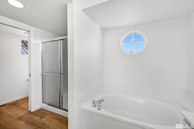 bathroom featuring wood finished floors, a stall shower, a garden tub, and visible vents