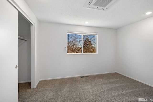 unfurnished bedroom with a textured ceiling, recessed lighting, carpet floors, visible vents, and baseboards