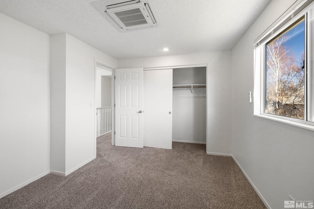 unfurnished bedroom featuring a textured ceiling, carpet floors, visible vents, baseboards, and a closet