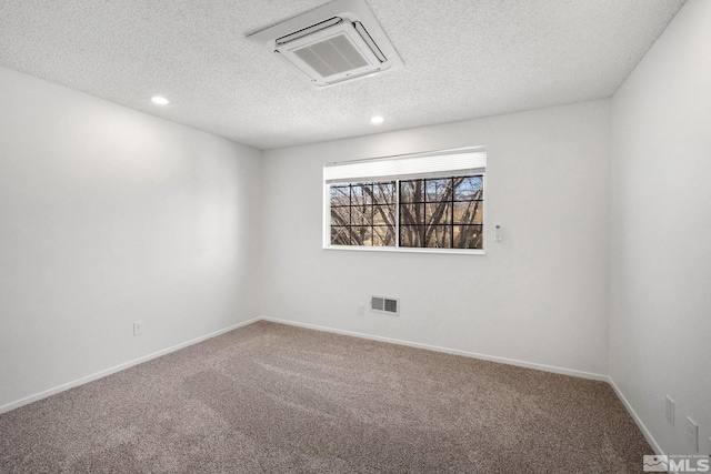 carpeted spare room featuring recessed lighting, visible vents, a textured ceiling, and baseboards