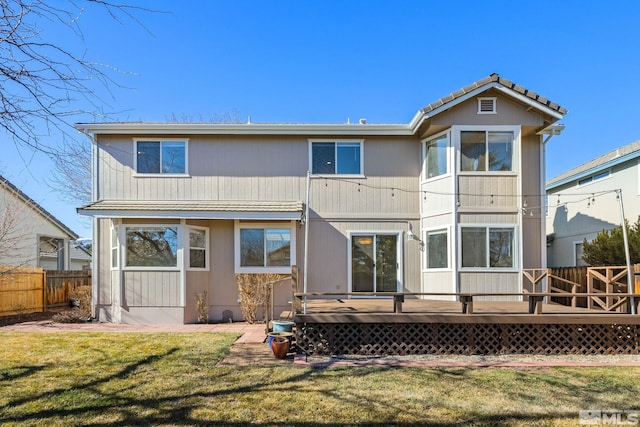 rear view of house featuring fence, a deck, and a yard