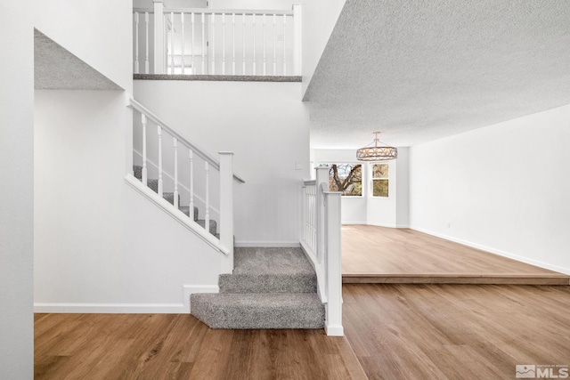 stairs featuring a textured ceiling, wood finished floors, and baseboards