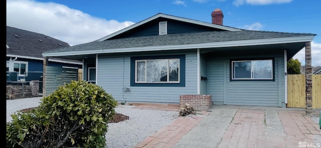 rear view of property with a shingled roof, fence, and a chimney